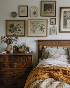 a bedroom with many pictures on the wall above the bed and dresser in front of it