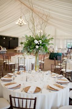 a table set up with white linens and flowers in a vase on top of it