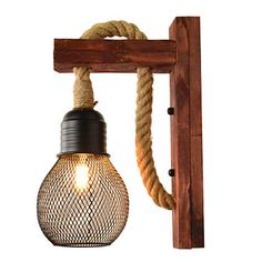 a light bulb hanging from a wooden beam with rope attached to the wall and an old fashioned lamp