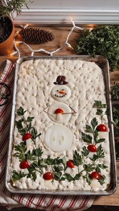 a homemade christmas cake decorated like a snowman with holly leaves and tomatoes on it