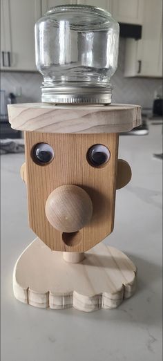 a wooden toy with a bottle on top of it's head and eyes in the shape of a man