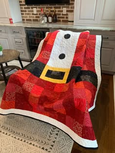 a red and black santa clause quilt on top of a chair in front of a fireplace