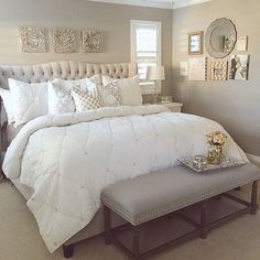 a white bed sitting in a bedroom next to a window with pictures on the wall