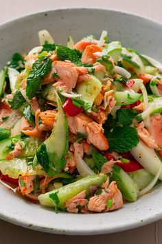 a white bowl filled with cucumber and salmon salad