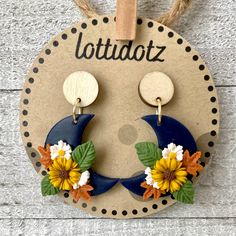 the earrings are decorated with sunflowers, leaves and crescent shaped wooden discs on a string