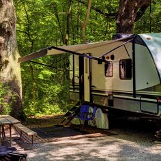 an rv parked in the woods next to a picnic table