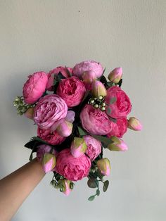 a hand holding a bouquet of pink flowers