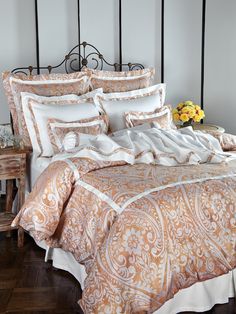 a bed with an orange and white comforter on top of it next to a table