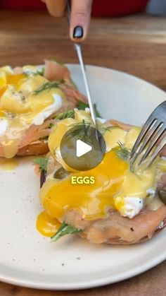 a person is cutting into some food on a white plate with a fork and knife