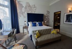 a bed room with a neatly made bed next to a chair and desk in front of a window