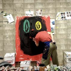 a man is painting on a large piece of art