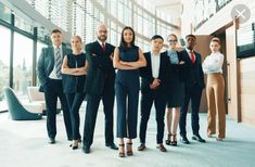 a group of business people standing in front of a large glass window with their arms crossed