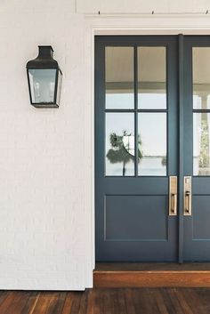 a blue front door with two sidelights and a lamp on the wall next to it