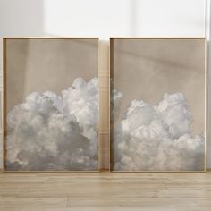 two paintings with white clouds on them in an empty room next to a wooden floor