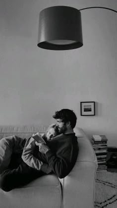 a man laying on top of a couch next to a lamp