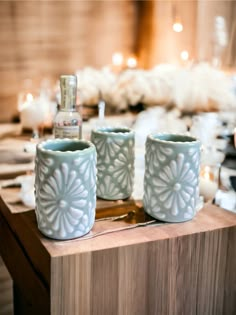 two blue cups sitting on top of a wooden table next to candles and other items