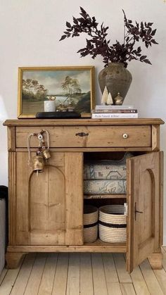 a wooden cabinet sitting on top of a hard wood floor next to a potted plant