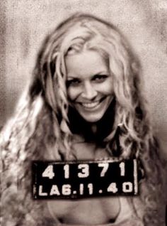 a woman with long blonde hair holding a license plate in front of her face and smiling at the camera