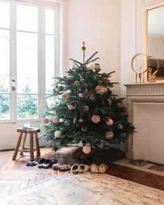 a small christmas tree in the corner of a living room with shoes on the floor