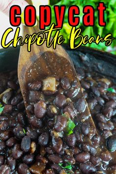 a wooden spoon filled with black beans on top of a table