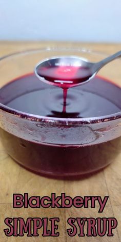 a spoon full of black berry syrup on top of a wooden table with the words blackberry simple syrup