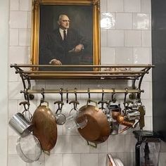 there is a painting on the wall above pots and pans hanging from a rack