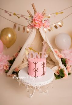 a pink and gold cake with the word no on it sitting in front of a teepee