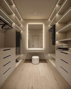 an empty walk in closet with lights on the ceiling and white drawers, along with a stool