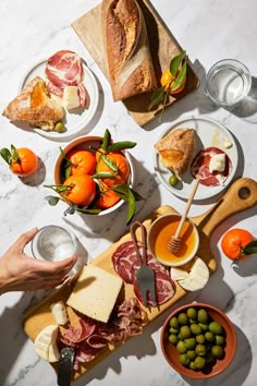 a table topped with plates and bowls filled with meats, cheeses and fruit