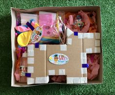 an open cardboard box filled with toys on top of a green carpeted floor,