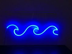 a neon sign that is lit up in the dark with blue lights on it and an ocean wave