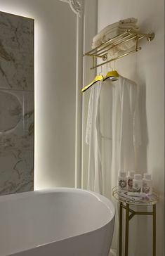 a white bath tub sitting next to a wall mounted shower head and towel rack in a bathroom