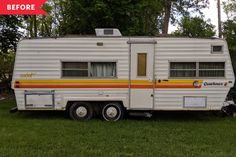 an old camper trailer is parked on the grass in front of some trees and bushes