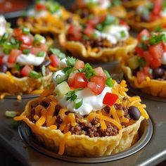 mini taco cups with cheese, black olives and sour cream on the top