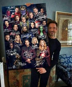 a man standing in front of a large poster with the cast of avengers 2 on it