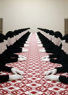 a group of people sitting on top of a red and white table covered in black cloths