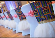 rows of white chairs with colorful sashes on them