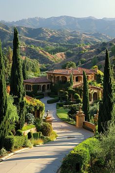 the driveway is lined with trees and bushes in front of a large house surrounded by hills