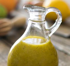 a glass bottle filled with yellow liquid sitting on top of a wooden table