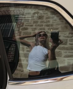 a woman taking a selfie in the side mirror of a car