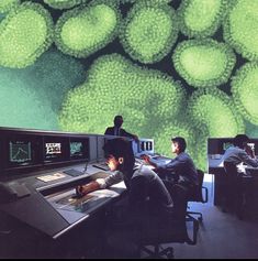 two men sitting at desks in front of monitors with green balls on the wall behind them