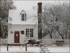 a white house covered in snow next to trees