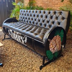 a black leather couch sitting on top of a gravel floor next to a brick wall