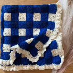 a blue and white crocheted blanket sitting on top of a wooden table