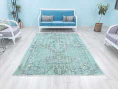 a living room filled with furniture and a blue rug on top of a hard wood floor