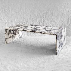 a marbled bench sitting on top of a white sheet covered floor next to a wall