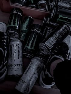 several cans and cans of monster energy drink sitting on a wooden shelf next to shoes