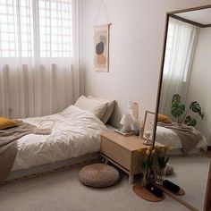 a bedroom with a bed, mirror and plant on the floor in front of it