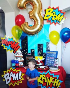 a young boy standing in front of a table with balloons and decorations on it's sides