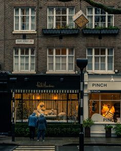 two people are walking down the street in front of a store